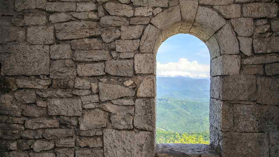 A doorway in a stone wall, looking out on to a field