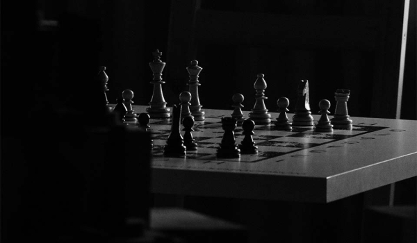 A chessboard in a room consumed by shadows