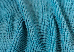 A close up photograph of the texture of a teal cloth