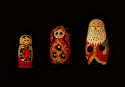 Three Christmas dolls laid side by side against a black background