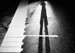 A black and photo of a long shadow cast across what looks like a piano keyboard