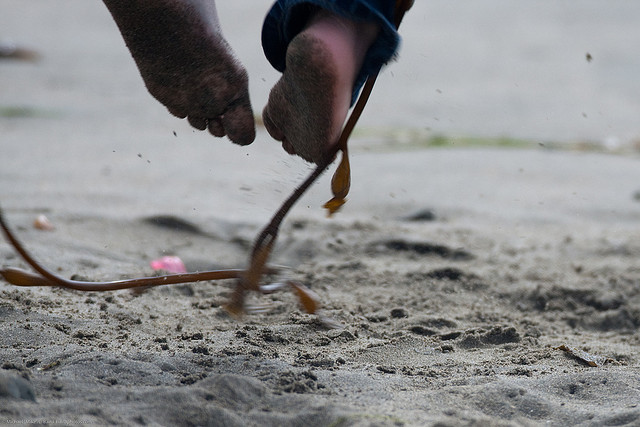 Child's feet jumping over a jump rope in the sand