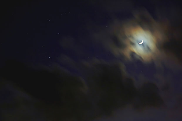 Crescent moon behind clouds. Photo by Adam Evans/Flickr