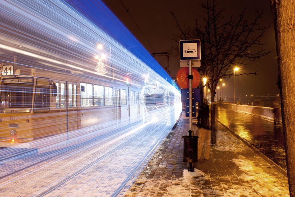 a tram in Hungary creates a streak of blue lights at night