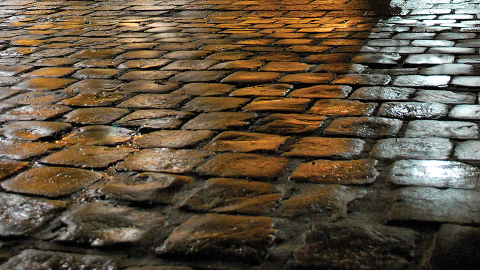 A detail of a cobbled street that gradates from brown to grey moving left to right