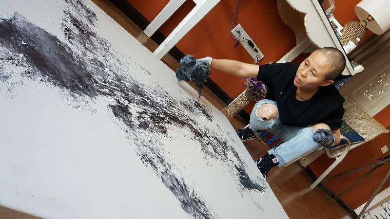 The artist and poet Liu Xia working with black paint on a large white canvas