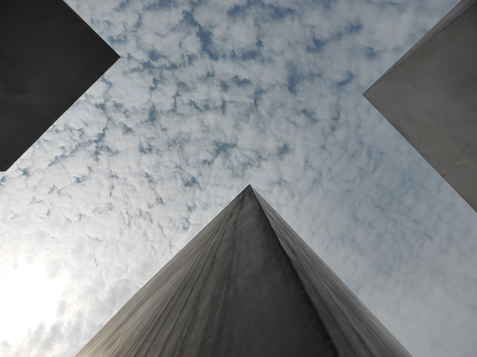 A photograph of a cloud-mottled sky seen from between four looming skyscrapers
