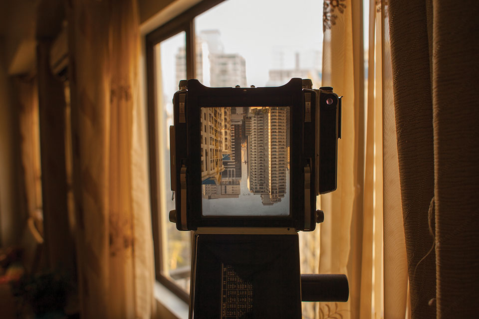 A camera is looking out a window at the city of Manilla. The image of the city is inverted in the camera's viewfinder.