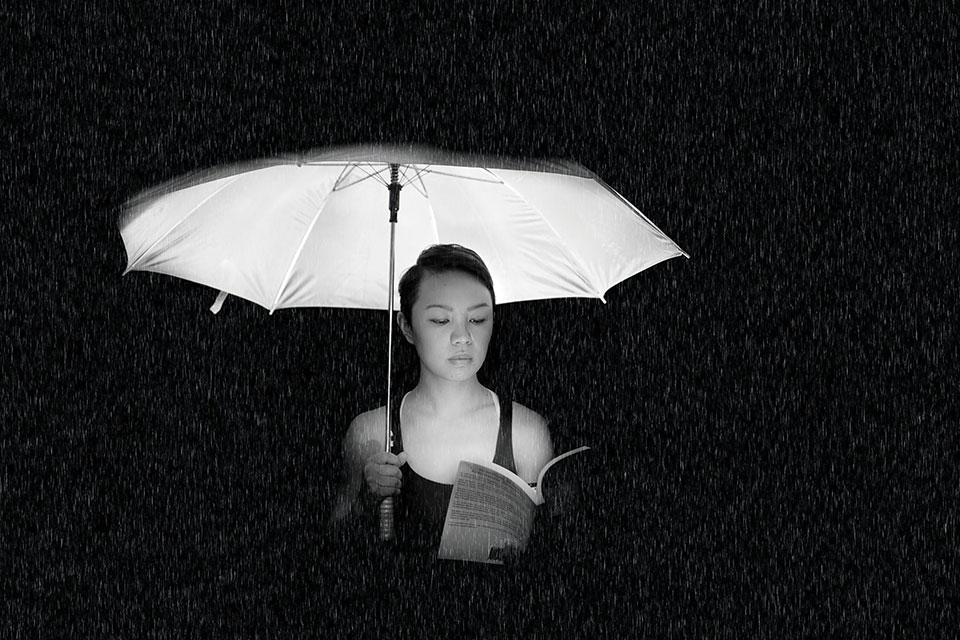 A woman reads a book underneath a lit umbrella