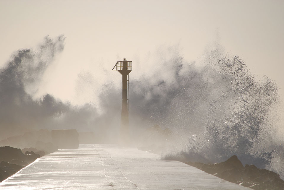 An observation tower rises out of the swirling froth atop a sea wall