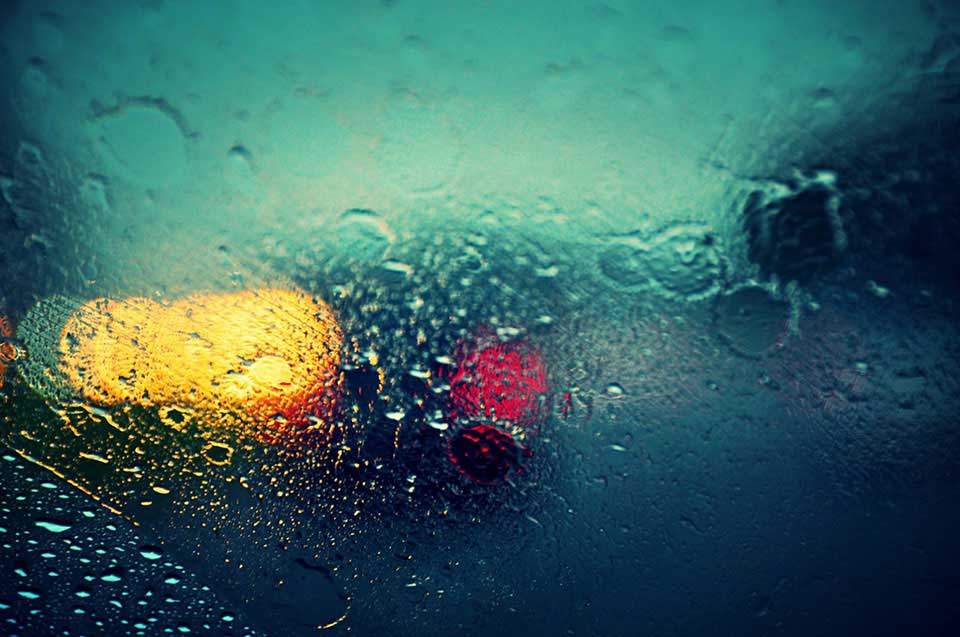 An abstract photograph of a car as seen through a rain streaked window