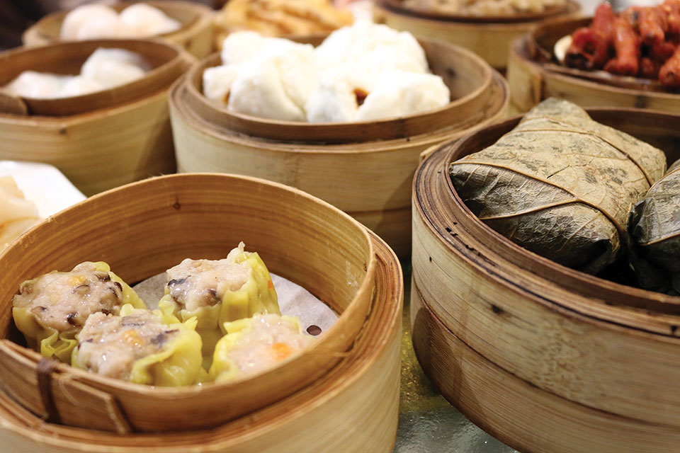 Small dishes of food in bamboo bowls on a dim sum cart