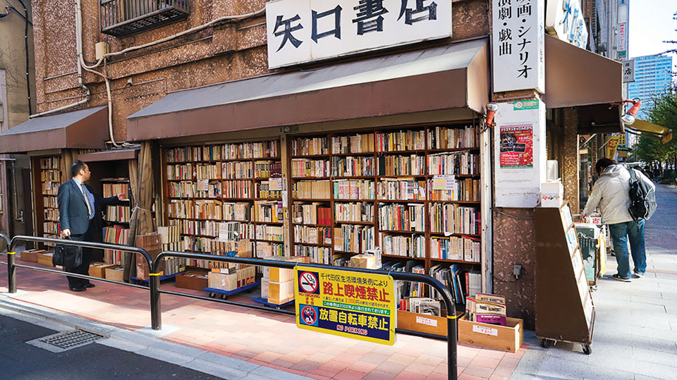 A Japanese salaryman pauses at a bookstall on the corner of two intersecting streets