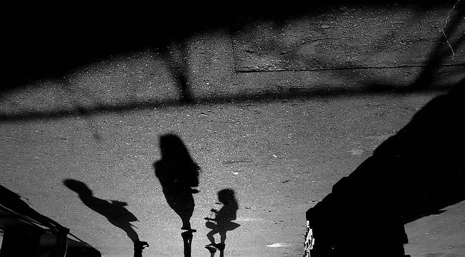 A black and white photograph of human shadows on the pavement