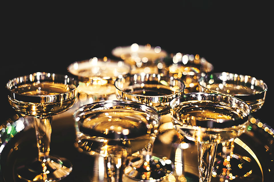 Crystal glasses filled with a gold liquid shot against a dark background
