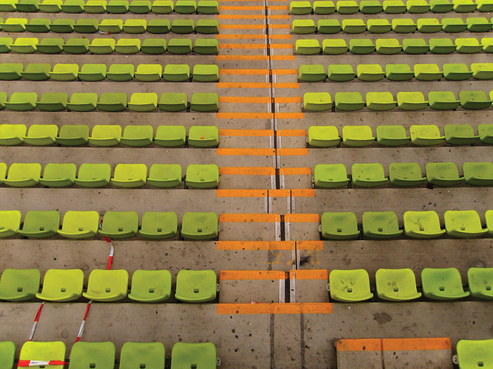 The empty seats of a soccer stadium as soon while looking down toward the field (which is not in the panel)