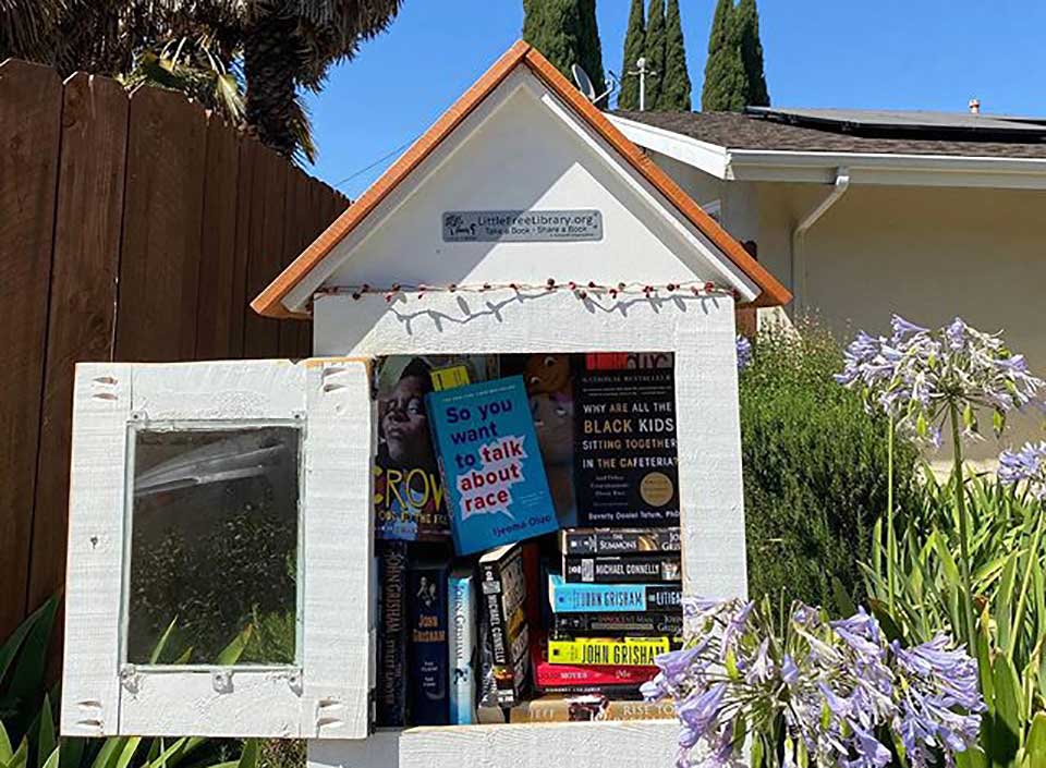 A small outdoor library with books inside an open door