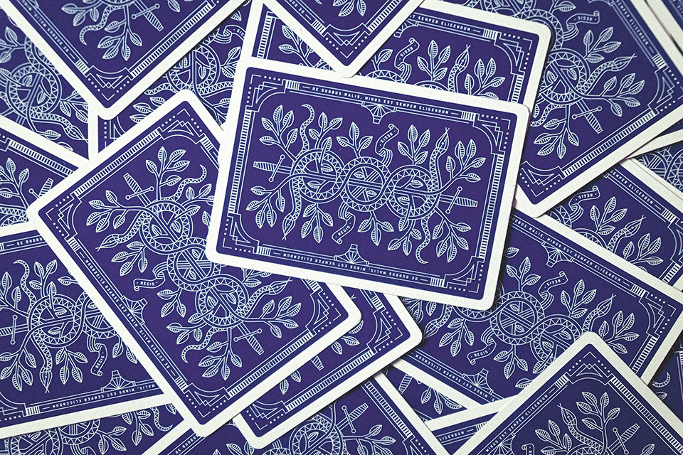 Playing cards with a stylized blue background are scattered on a flat surface