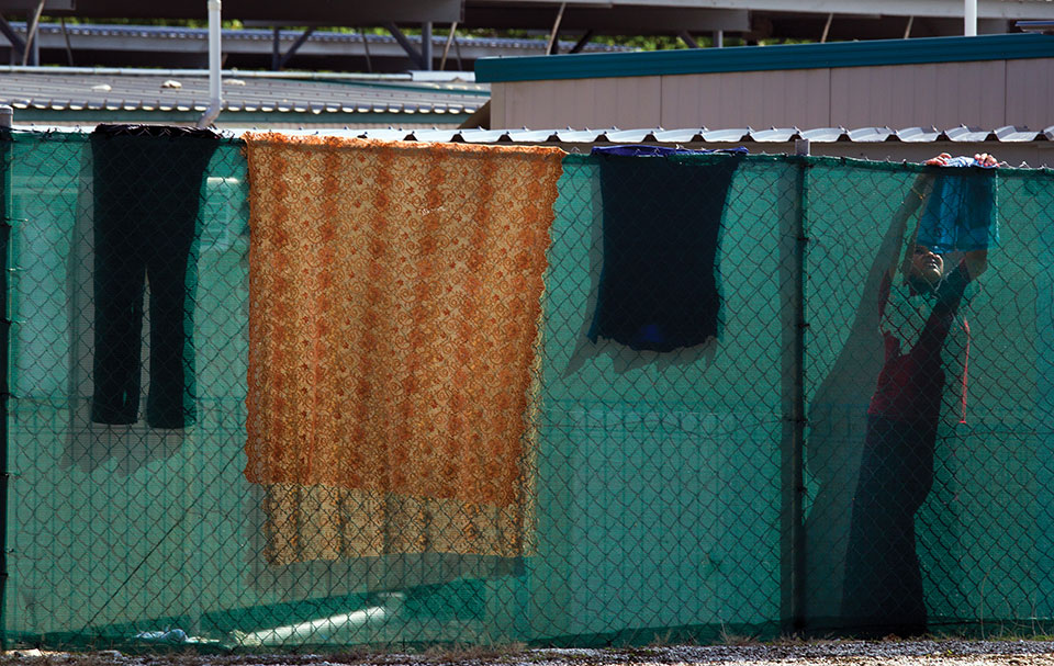 Clothes and other textiles hang on a chain-link fence surrounding tents