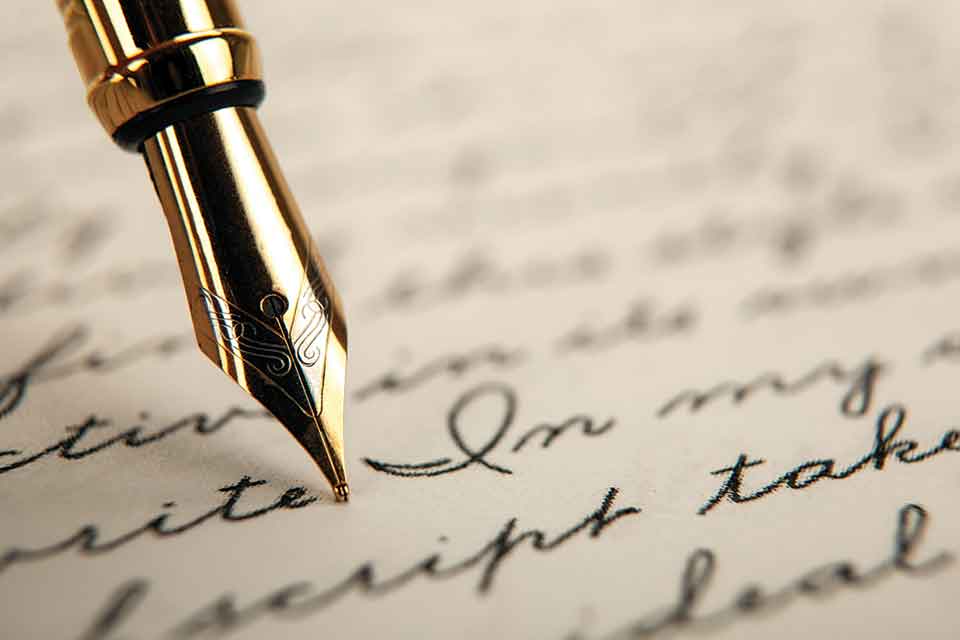 A photograph of a fountain pen writing in cursive on paper