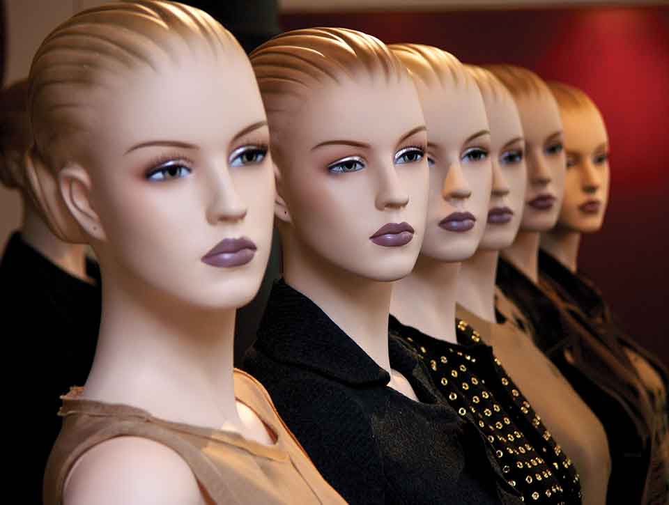 A row of mannequin busts with the same face but different outfits