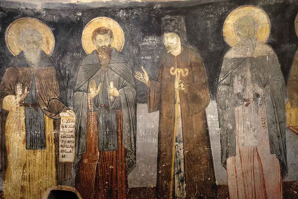 A photograph of a weathered religious painting with four male figures