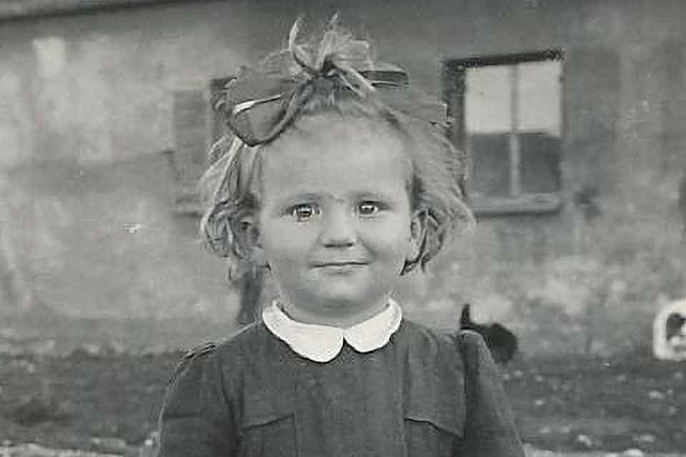 A black and white historical photograph of a young girl smiling at the camera