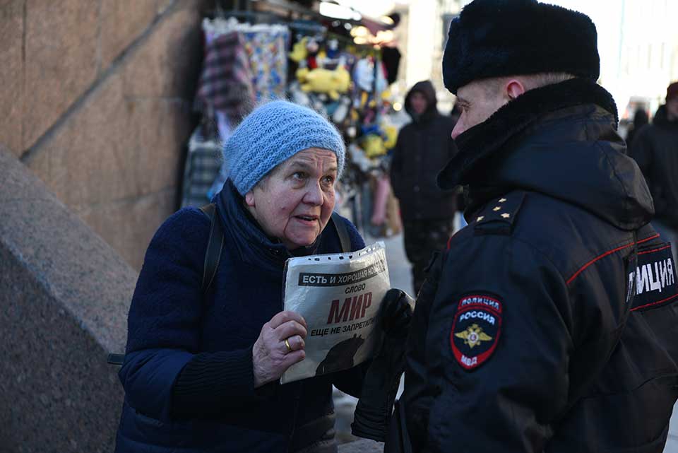 A photograph of an elderly woman holding a pamphlet confronting a police officer