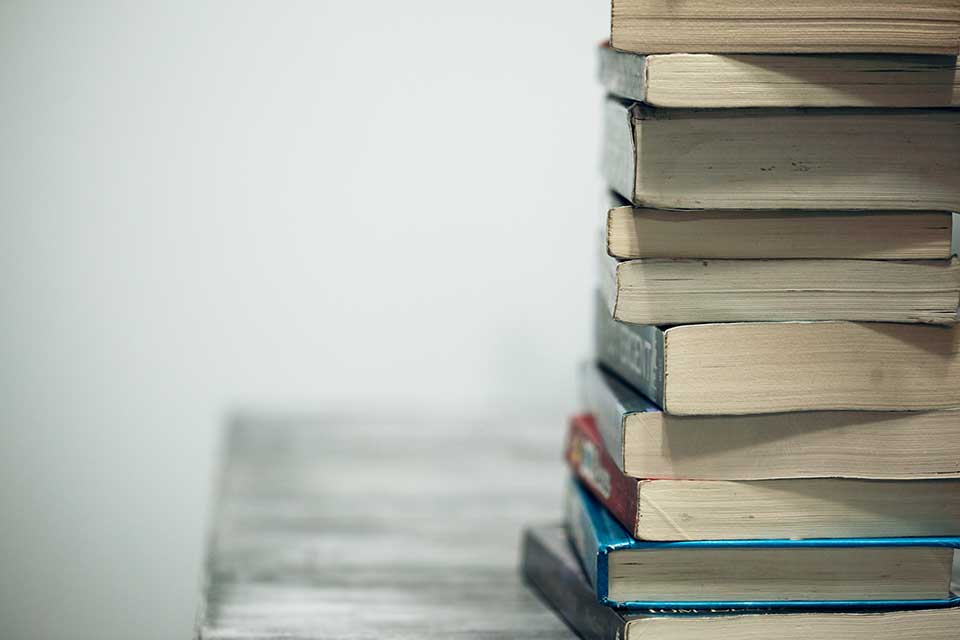 A photograph of a stack of books against a neutral white background