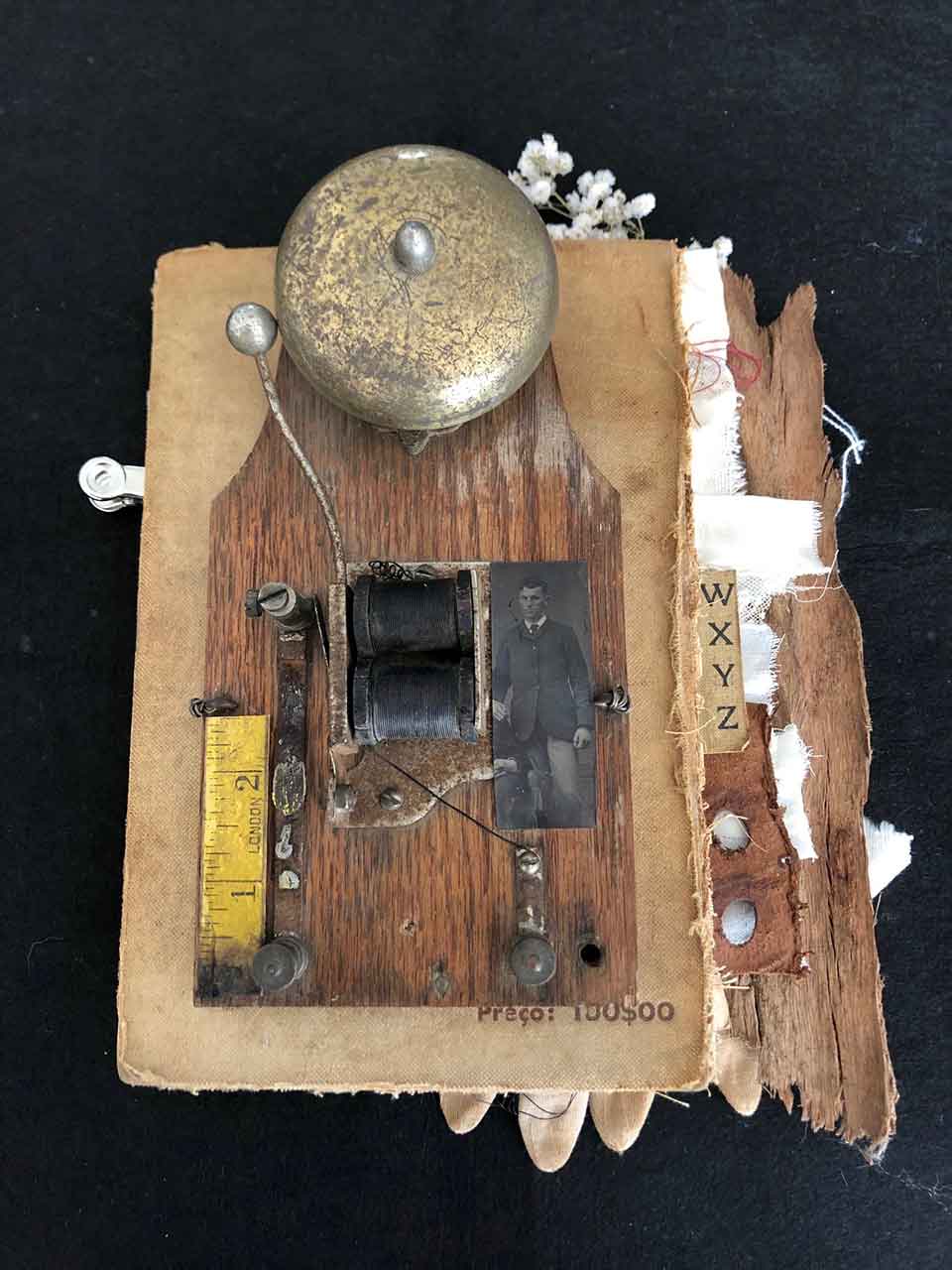 A crude hammered bells and wires mounted on the deconstructed interior of a book