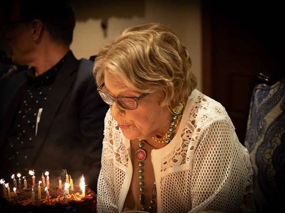 A photograph of Delores Neustadt blowing out candles on a birthday cake