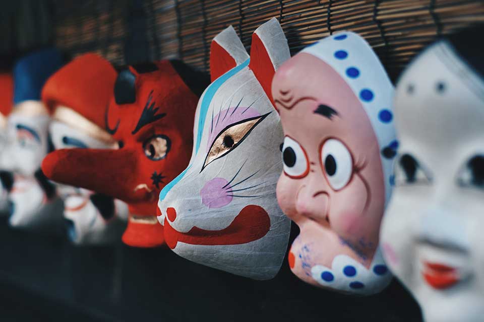 A photograph of a number of painted porcelain masks on a shelf