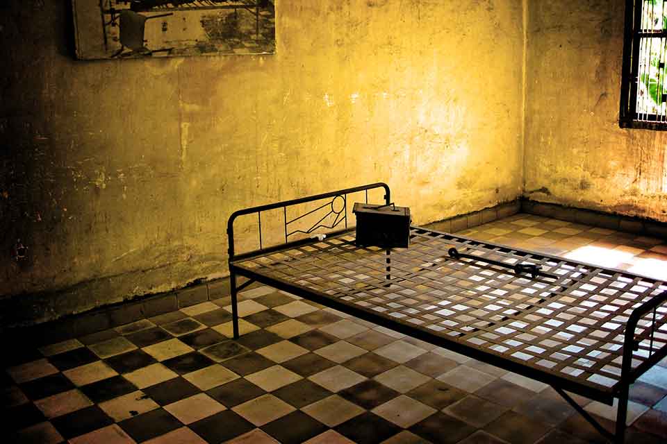 A photograph of a cot in a dimly lit prison cell