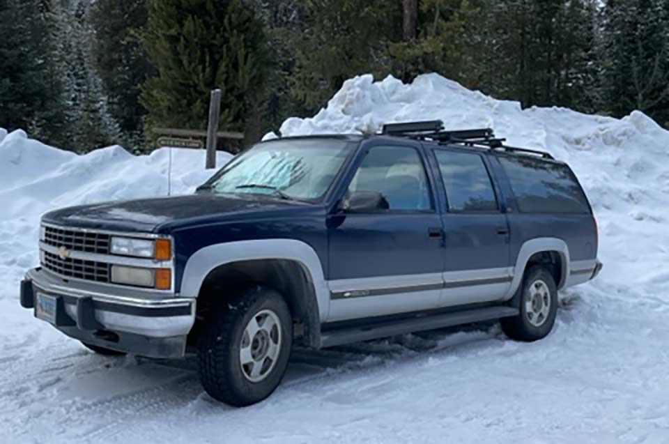 A photograph of a Chevy Suburban covered in snow