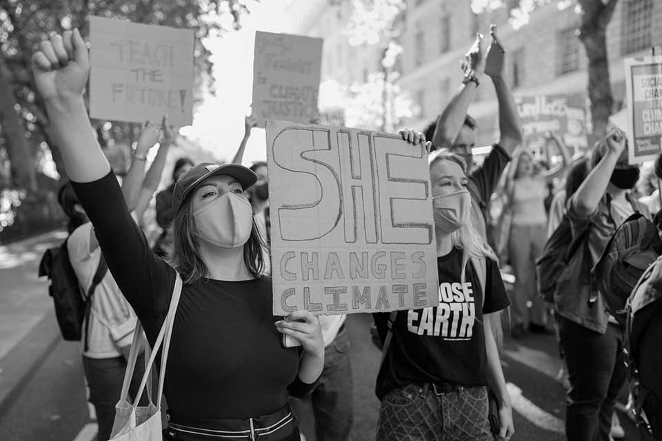 A black and white photograph of young people, many wearing masks, protesting climate inaction