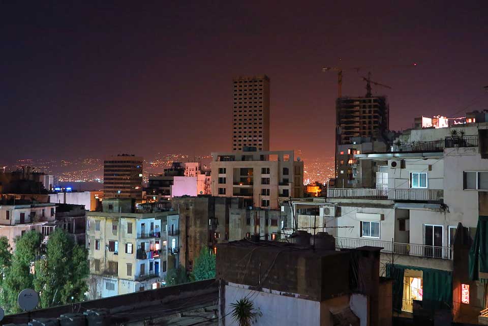 A photograph looking over the roof line at the city of Beirut at night