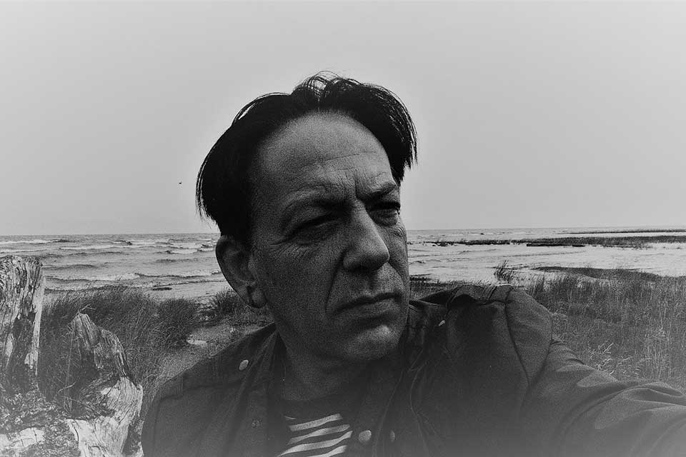 An underexposed black and white photograph of Jean-Baptiste Para on the shore of Lake Baikal