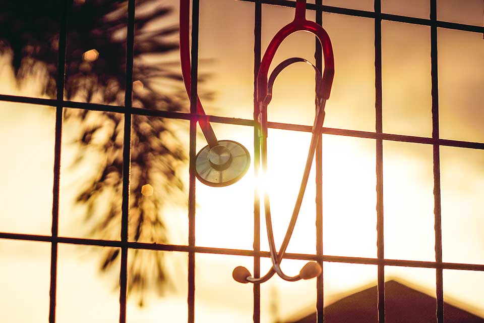A photograph of a stethoscope hanging into a window through which the sun is shining