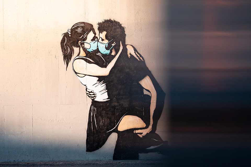 An illustration of a man and woman embracing. Both are wearing surgical masks