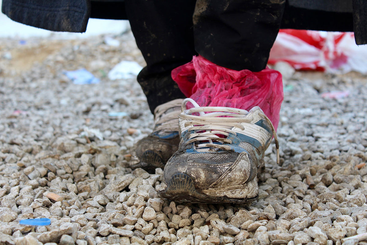 A refugee’s shoes are worn, wet, and muddy after a long journey. These shoes are owned by Ali, a Yazidi refugee who traveled from Iraq to Preševo, Serbia, to avoid persecution (photo by Meabh Smith / Trócaire).