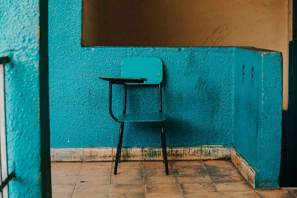 A children's school desk painted blue, sitting in front of a wall painted similarly blue
