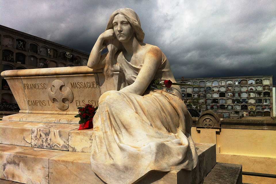 A statue of a reclining figure in a cemetery
