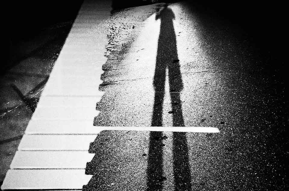 A black and photo of a long shadow cast across what looks like a piano keyboard