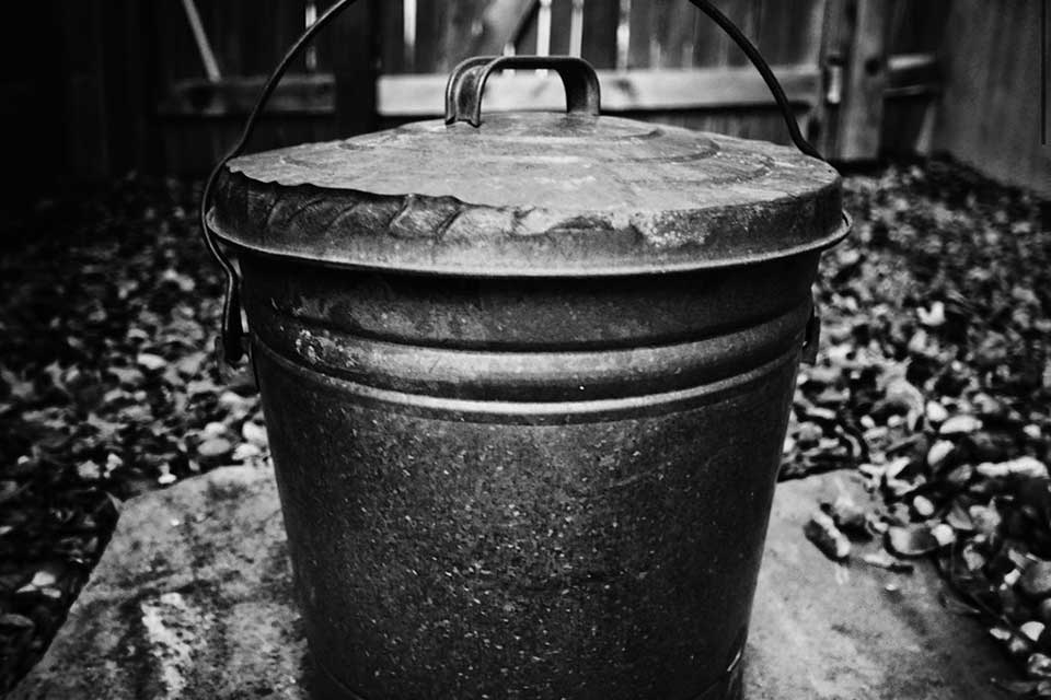 A black and white photograph of a black metal pail
