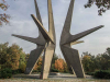 A photograph of an outdoor monument featuring three spiky geometric figures rising up out of the ground.