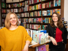 Two women smile at the camera in a bookstore