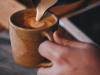 A photograph of someone pouring cream into coffee in a cup