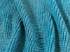 A close up photograph of the texture of a teal cloth