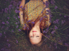 A photograph looking down on a young woman who is laying in the grass, eyes closed. Photo by Amy Treasure on Unsplash.