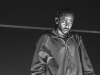 A black and white photo of Kendrick Lamar in performance, his eyes closed